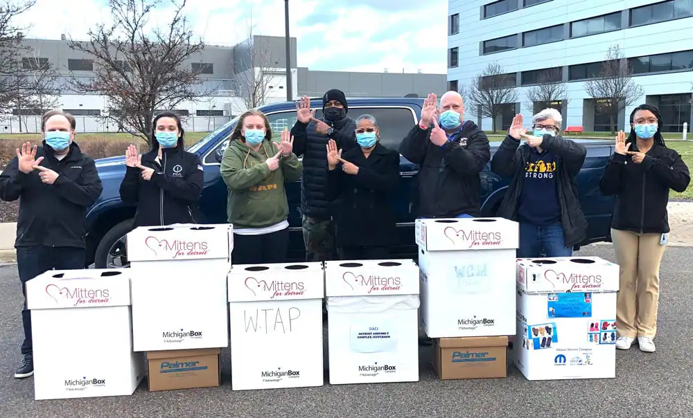 Group of volunteers with donation boxes at MFD Staging event in front of buildings.